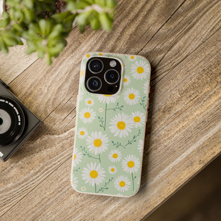 Eco-friendly daisy phone case on a wooden table, biodegradable floral design, fits many iPhone and Samsung models, durable protection.