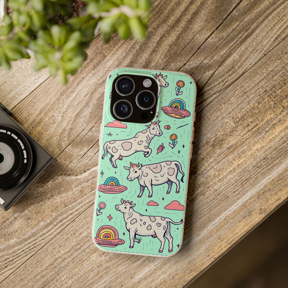 Eco-friendly iPhone case with whimsical cow and rainbow design, shown on wooden table. Compatible with many iPhone and Samsung models.