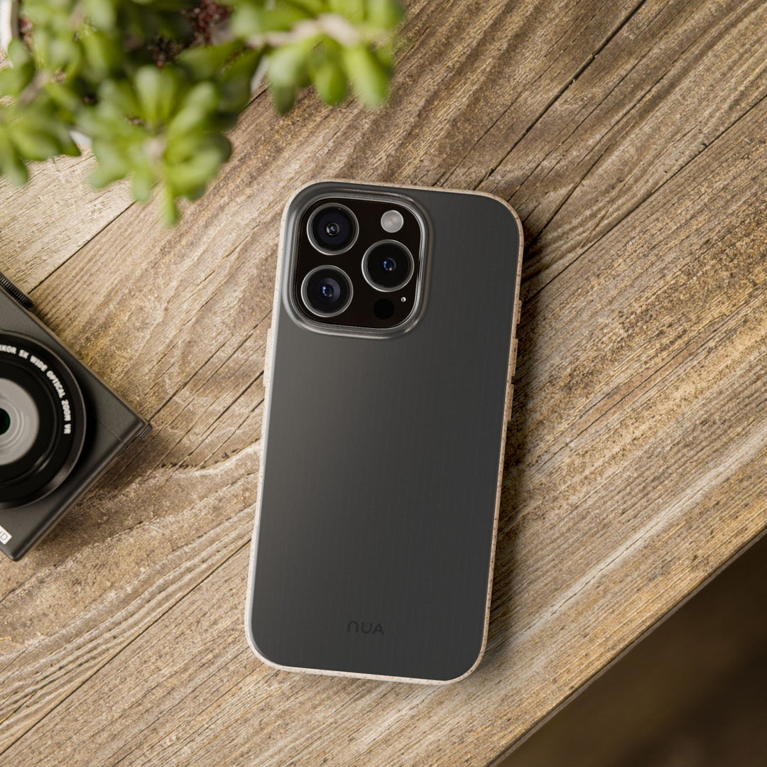 Sleek black eco-friendly phone case on a wooden table next to a camera, ideal for iPhone and Samsung models.