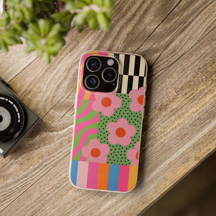 Groovy Garden Retro Patchwork iPhone case on wooden table, eco-friendly, durable, stylish design with vibrant colors and floral patterns.
