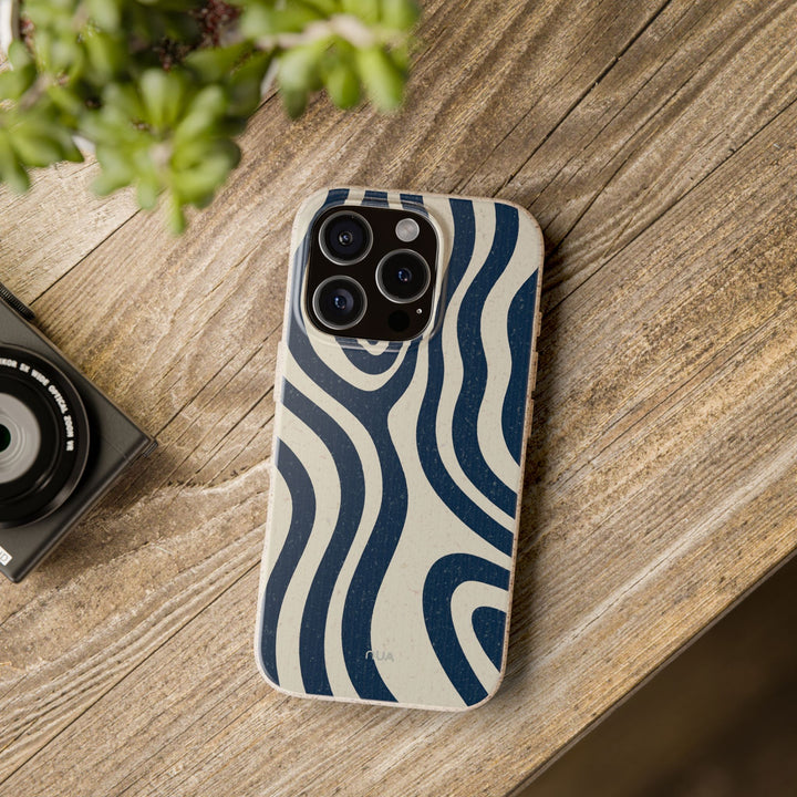 Midnight Drift biodegradable phone case with navy and cream wave pattern on wooden table, eco-friendly and durable for iPhone and Samsung.
